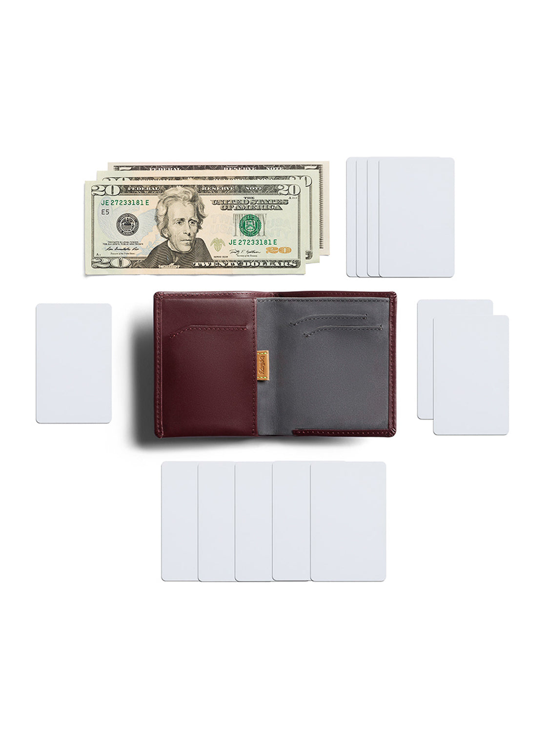 A Bellroy Note Sleeve Wallet in burgundy and gray is open to show its interior, with U.S. dollar bills above it and blank white cards arranged around it on a white background.