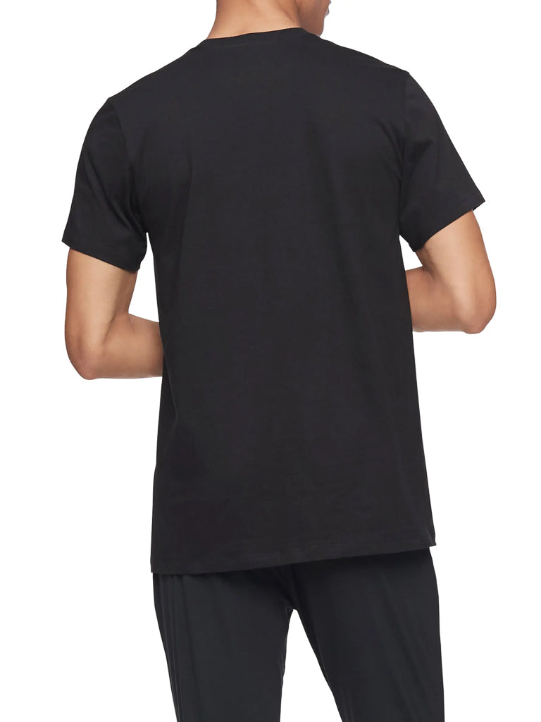 Someone is seen from the back wearing a Calvin Klein NB4051 3-Pack Cotton Classic Crewneck Tee in black with matching black pants, posed against a white background.