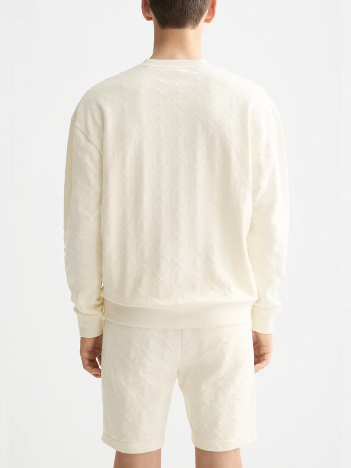 A person faces away wearing Scotch & Soda’s 181532 Jacquard Terry Sweatshirt in light cream, featuring a subtle textured pattern that adds depth to the casual look against a plain white background.