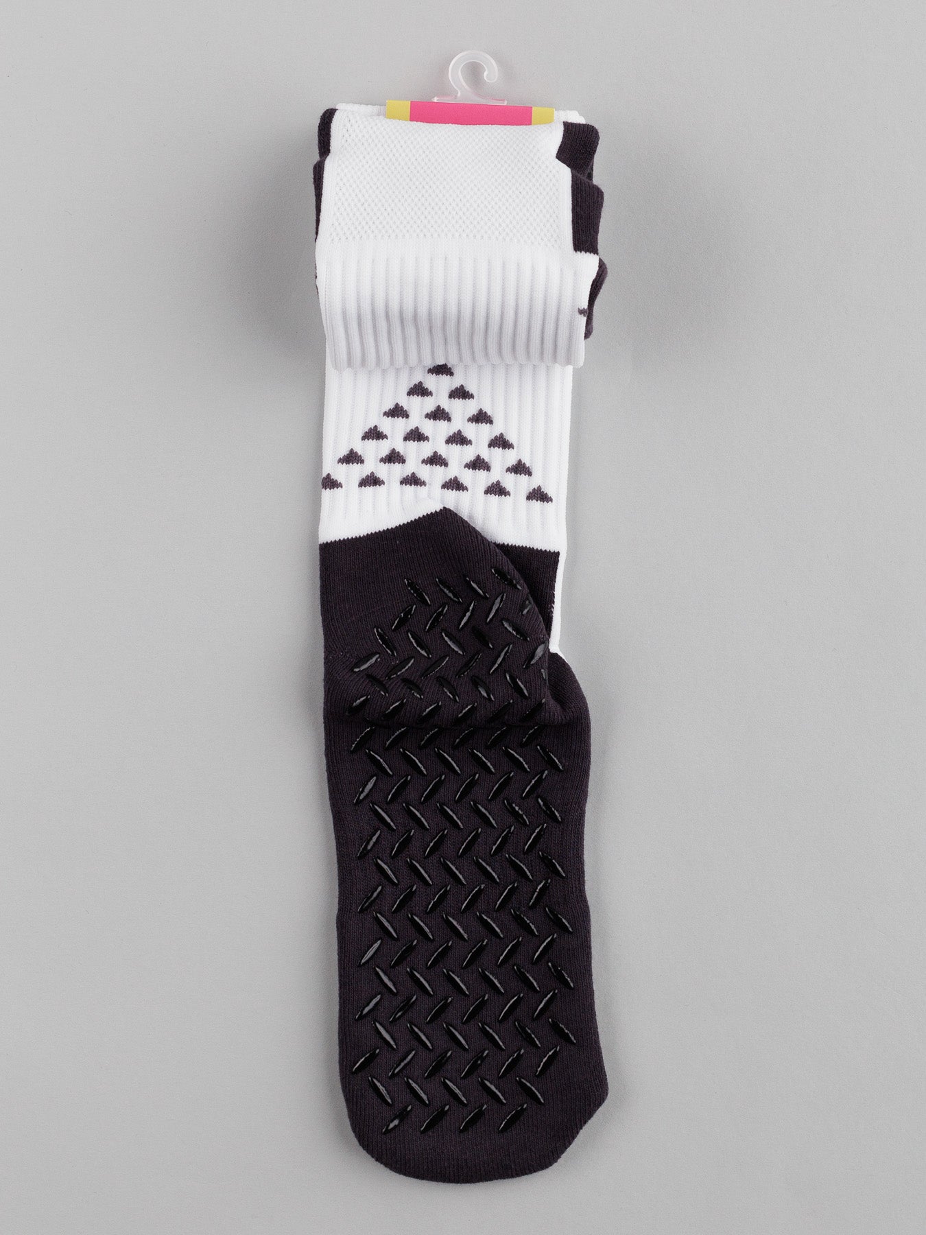 The folded ID Menswear Grip Sports Socks, featuring geometric patterns with black triangles and anti-slip design for improved performance and comfort, are displayed on a gray background.