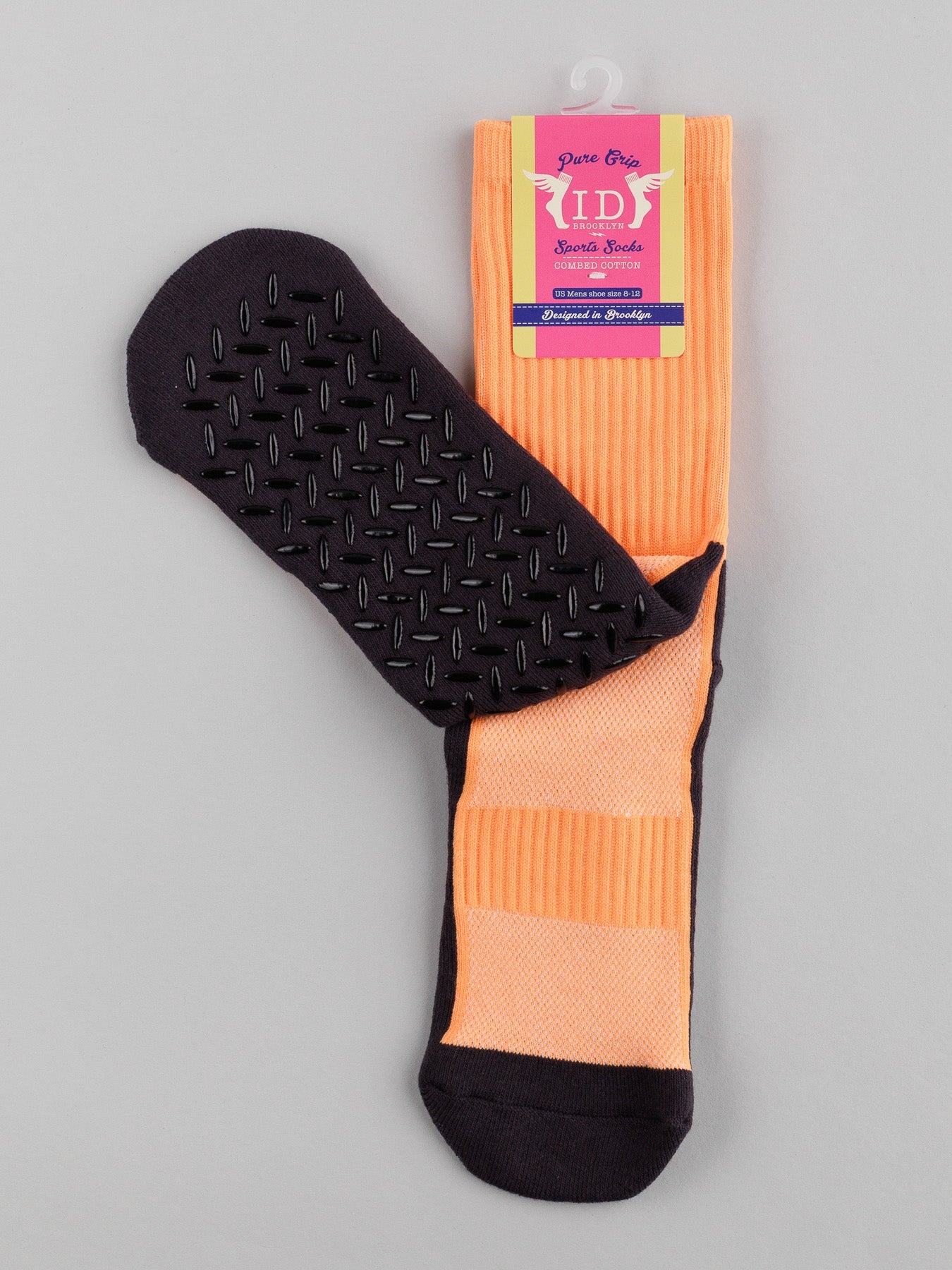 The Grip Sports Socks by ID Menswear are orange, knee-high with black soles and anti-slip grip dots. They feature a folded top for comfort and performance, displayed in purple cardboard packaging with decorative text.