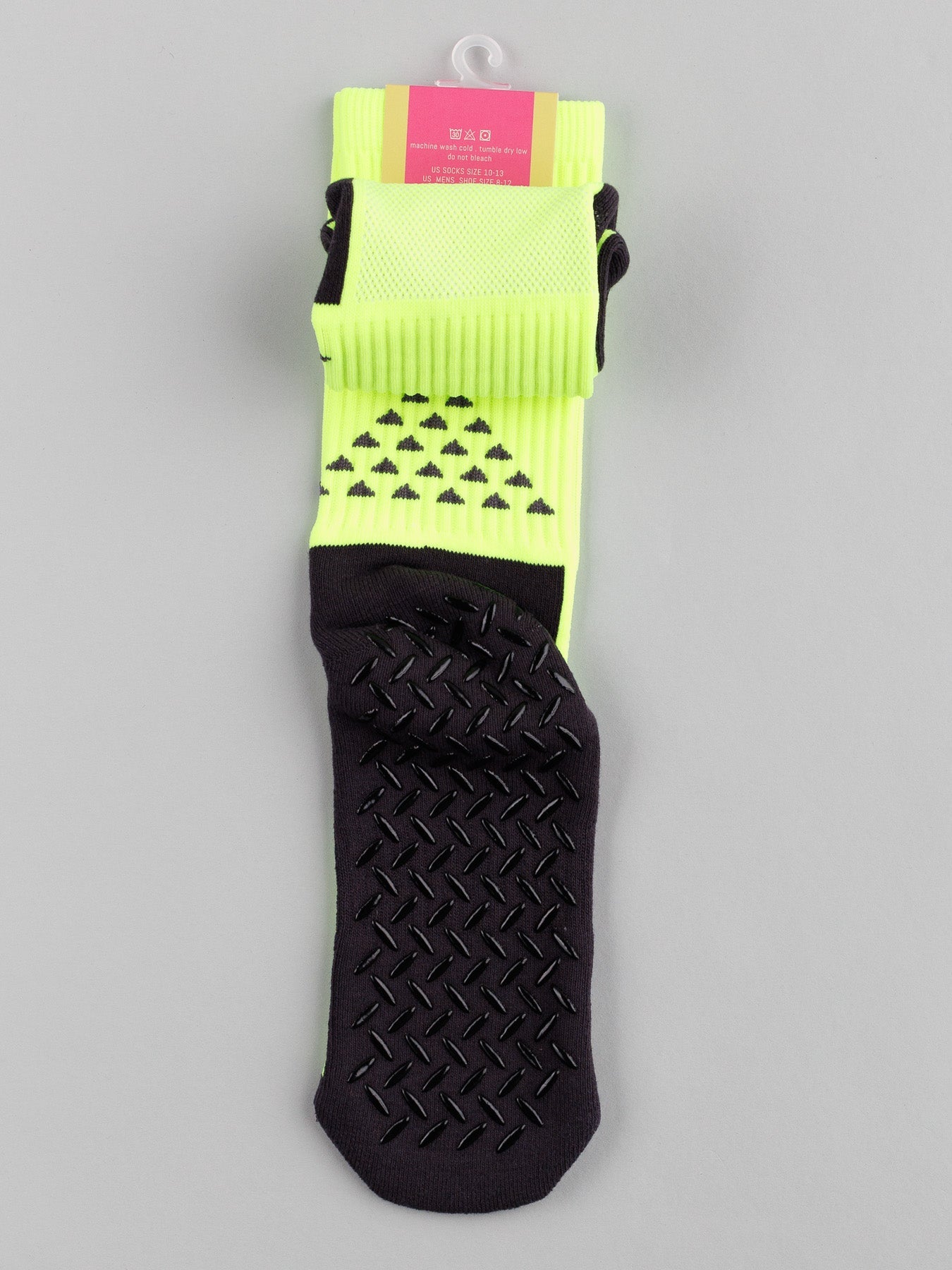 The Grip Sports Socks by ID Menswear are neon yellow and black with a pattern of small black triangles. These high-performance socks feature an anti-slip, textured sole for enhanced grip and come packaged with a stylish pink and white label.