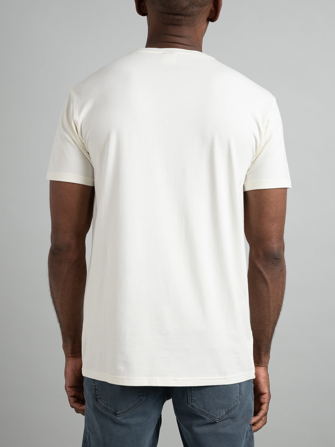 A person is shown from the back against a gray background, wearing a plain white Bello Bamboo Blend Rolled Neck Tee by ID Menswear and blue jeans.