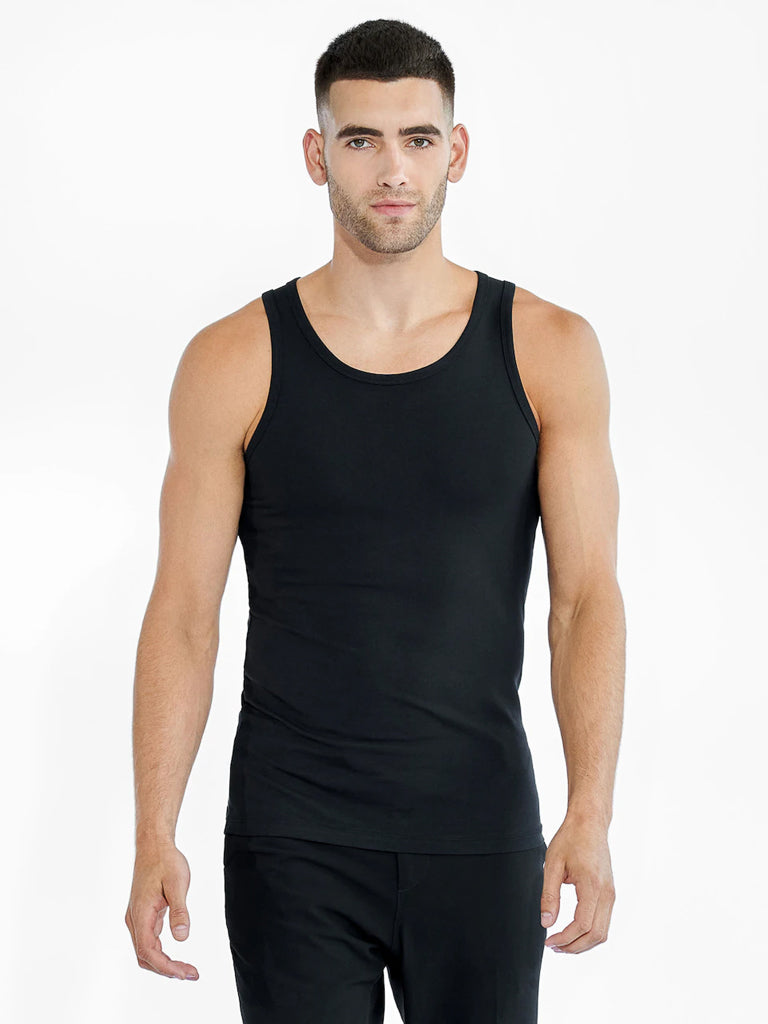 A man with short hair wears a Bread & Boxer 2 Pack Tank Top Cotton Stretch and black pants. He stands against a plain white backdrop, looking ahead with a neutral expression.