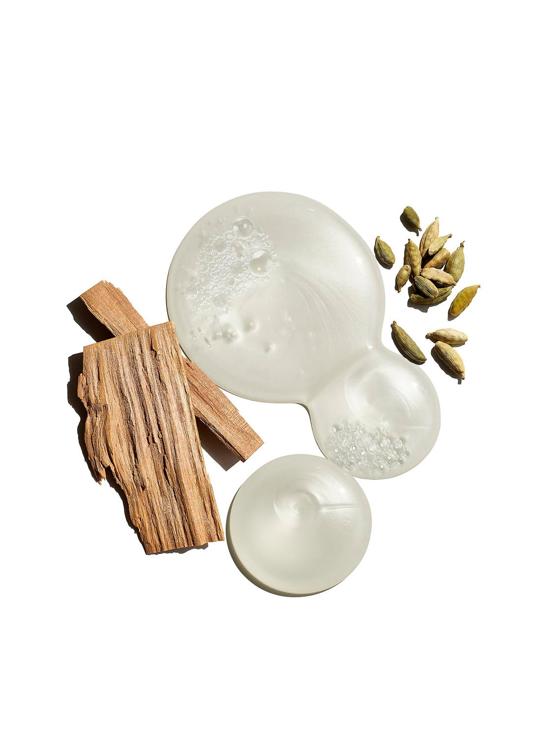 Jack Black’s Body and Hair Cleanser is shown as a clear liquid in three puddles with wooden sticks and green cardamom pods, highlighting the power of natural ingredients on a white background. Inspired by Jack Black’s clean, effective skincare.