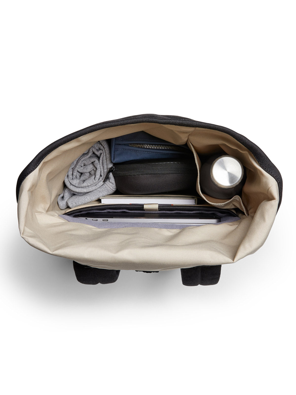 A top-down view of the Bellroy Oslo Backpack shows a rolled-up shirt, zippered pouch, water bottle, and a laptop or tablet in its dedicated sleeve, all neatly organized inside this minimalist bag.