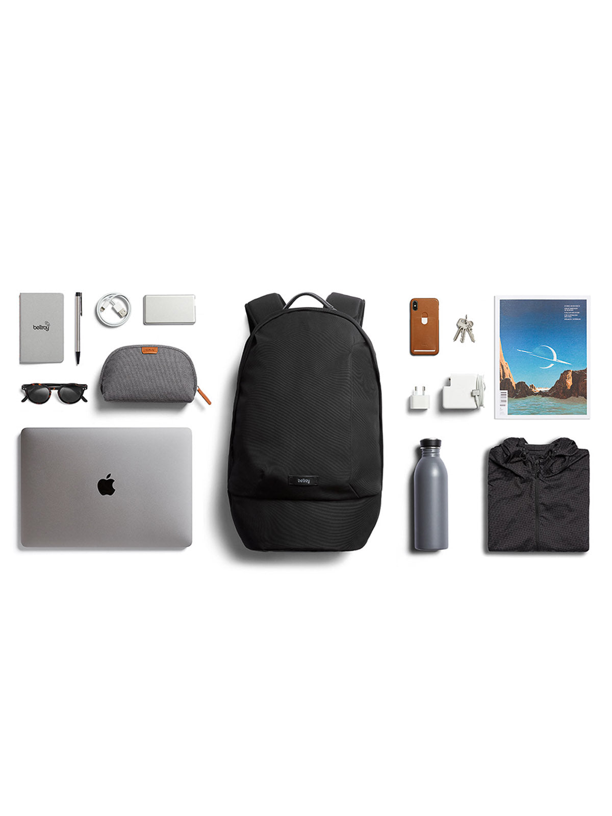 A stylish flat lay features the Bellroy Classic Backpack - 20L, crafted from recycled materials and surrounded by daily essentials like a laptop, sunglasses, notebook, pen, watch, earphones, cables, phone, water bottle, keys, pouch, magazine, and jacket.