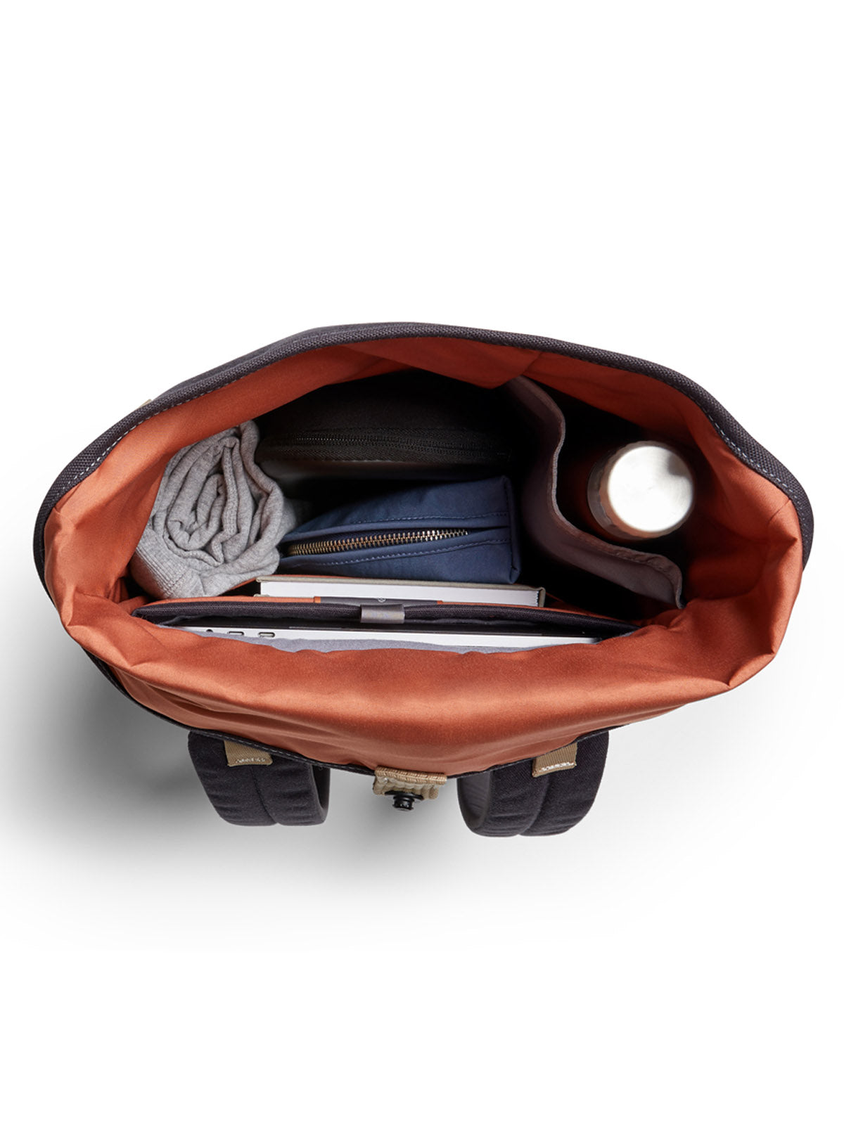 A top-down view of the Bellroy Oslo Backpack open, displaying a rolled-up shirt, zippered pouch, water bottle, and multiple books or notebooks neatly arranged inside.