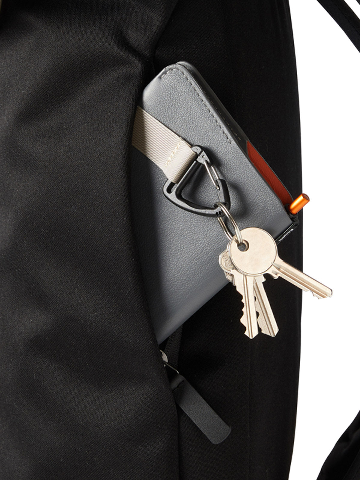 A close-up of a gray wallet with keys on a keyring, partially tucked into the side pocket of the Bellroy Oslo Backpack—a sleek, minimalist design.