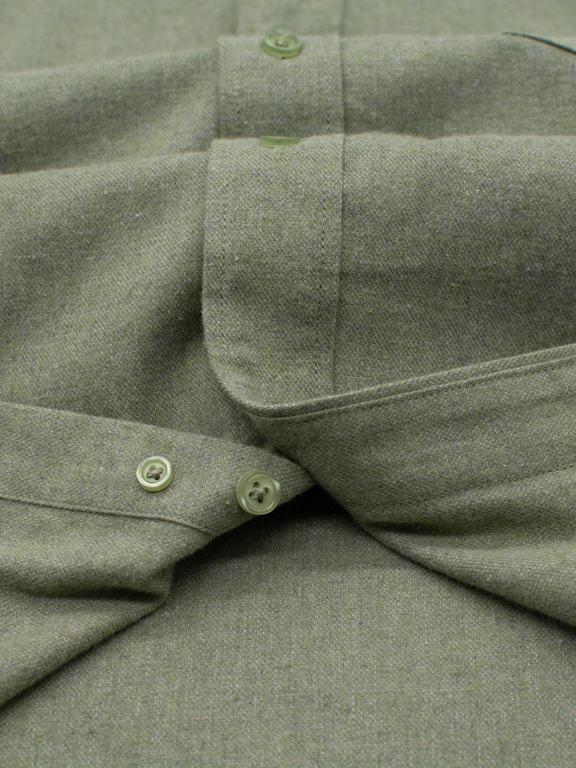 Close-up of the Max Brushed Flannel Shirt by ID Menswear, featuring a folded green button-down collar with matching buttons. The 100% cotton fabric is textured, showcasing detailed stitching and a soft weave. Fastened buttons highlight its craftsmanship.