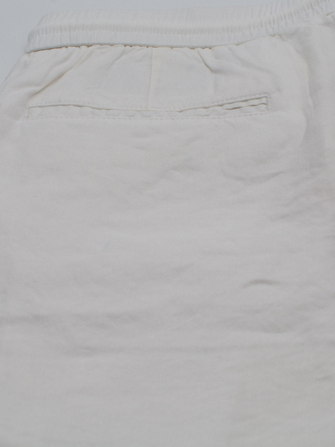 Close-up of the Driggs Linen Blend Short by ID Menswear. These light beige shorts feature a soft, linen-blend fabric with subtle creases—ideal for warm weather. The back pocket is neatly sewn on, and an elastic waistband ensures comfort.