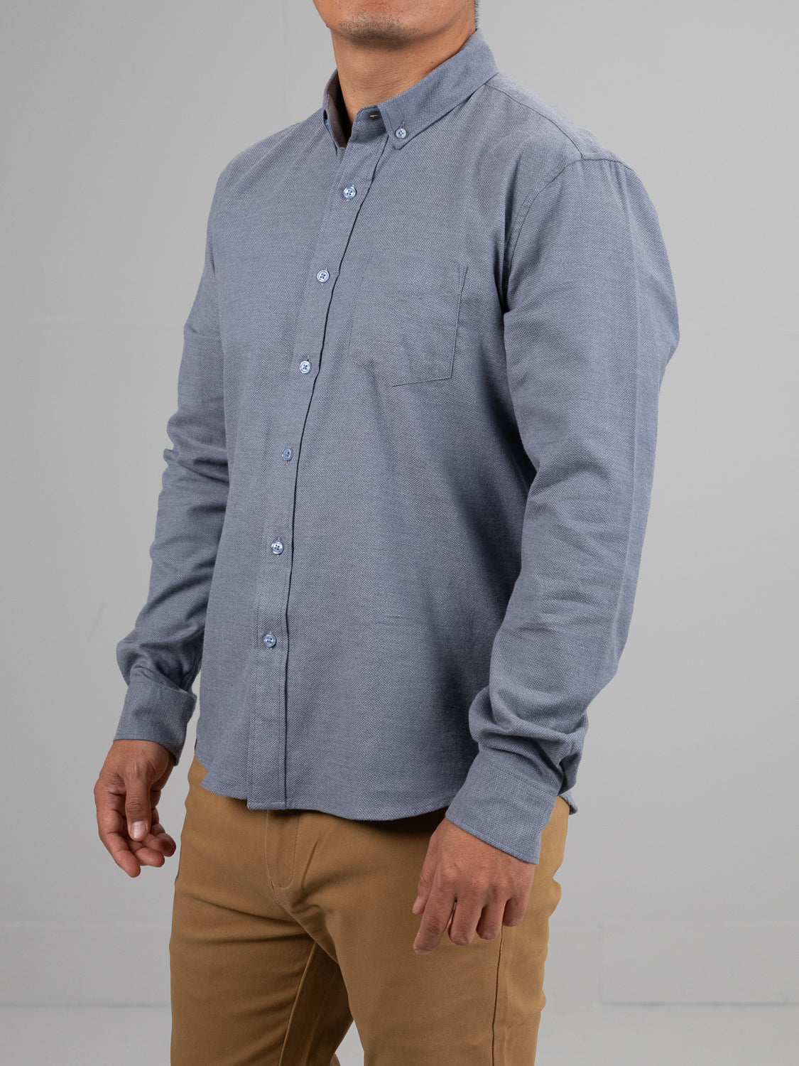 A headless figure in an Amir Solid Flannel Textured Dobby Shirt by ID Menswear, featuring a pocket and crafted from lightweight comfort fabric, is tucked into khaki pants against a plain background.
