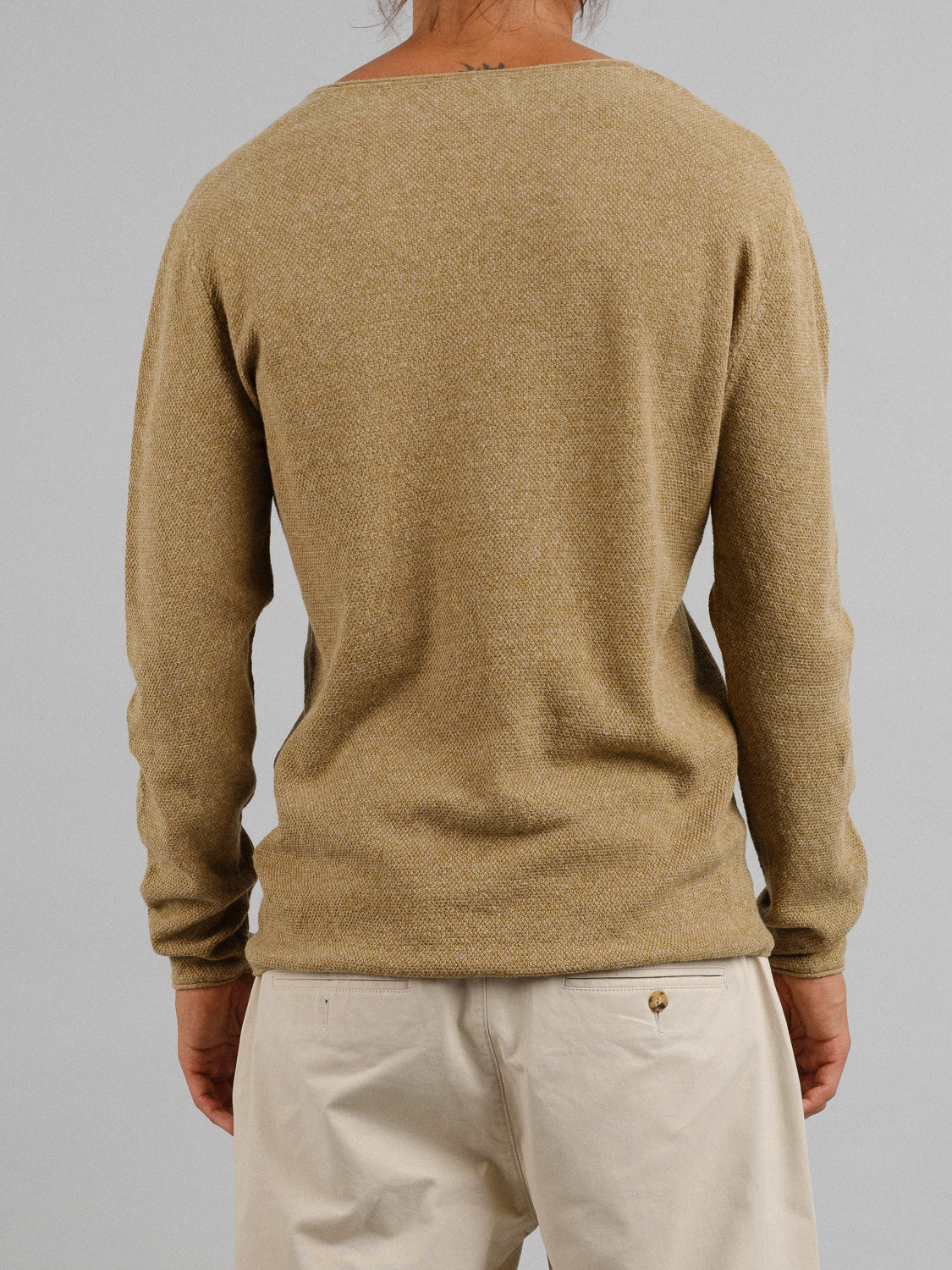 A person is shown from behind wearing an Amalfi Deep V Knitted Top by ID Menswear and light-colored pants, standing against a plain gray background.