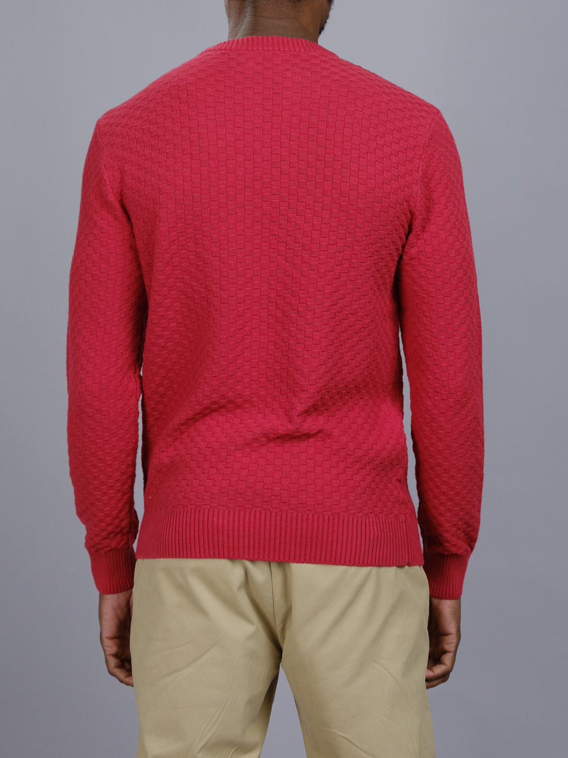 A person in a stylish ID Menswear Turku Cotton Sweater and khaki pants is viewed from the back against a gray background.