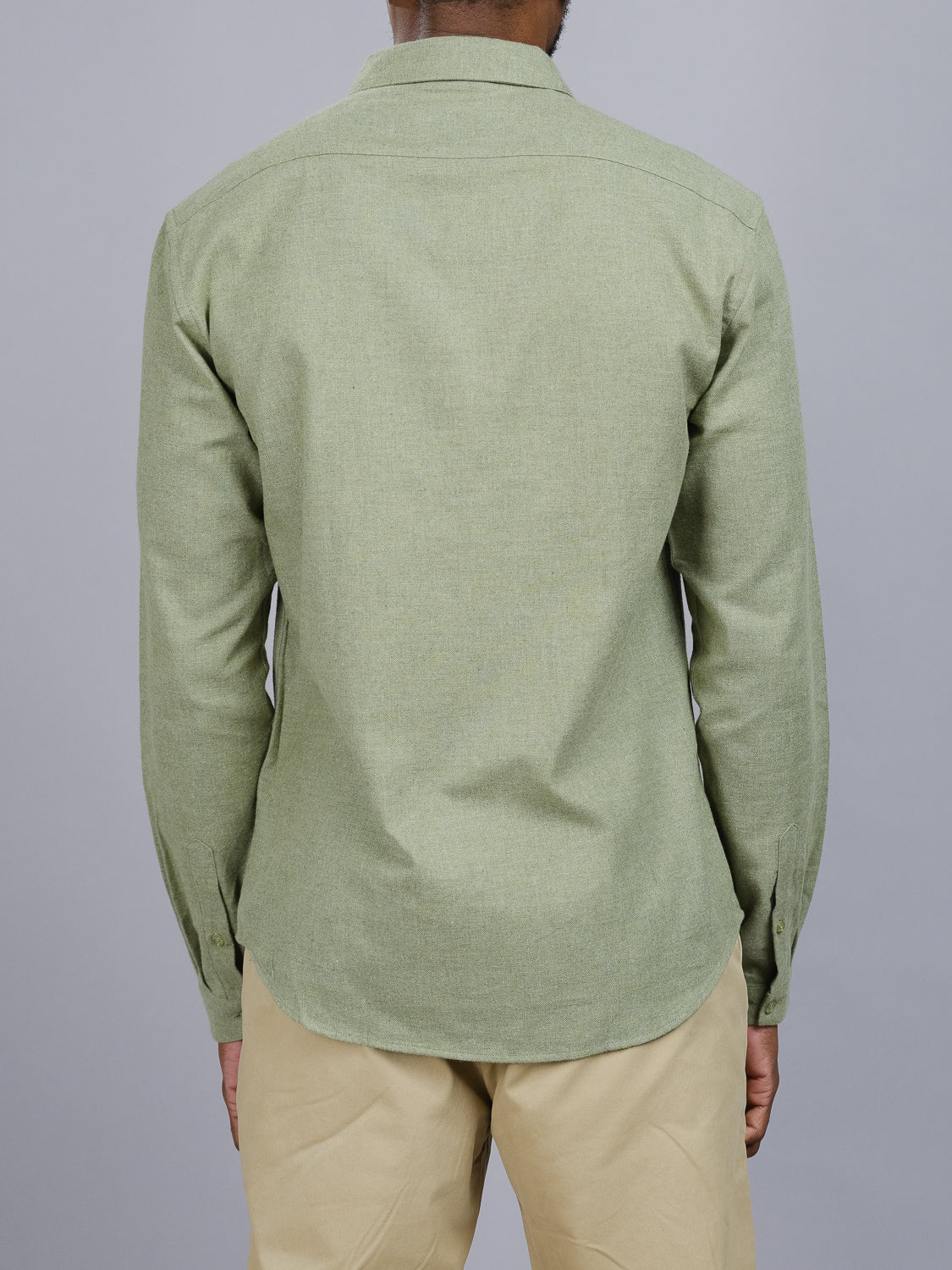 A person wearing the Max Brushed Flannel Shirt in light green from ID Menswear, a 100% cotton long-sleeve button-up, stands with their back to the camera. Theyre paired with classic light khaki pants against a plain gray background.