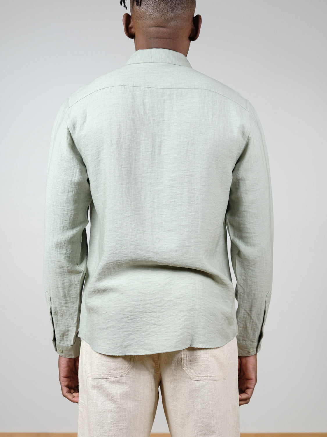 A person, seen from behind against a plain background, wears the ID Menswear Lagos Long Sleeve Shirt in light green with light beige pants.