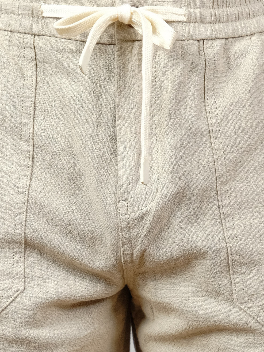 Close-up of the Sahara Linen Cotton Pant by ID Menswear, featuring a beige textured fabric, elastic waistband with white drawstring bow, front pockets, and a relaxed fit.