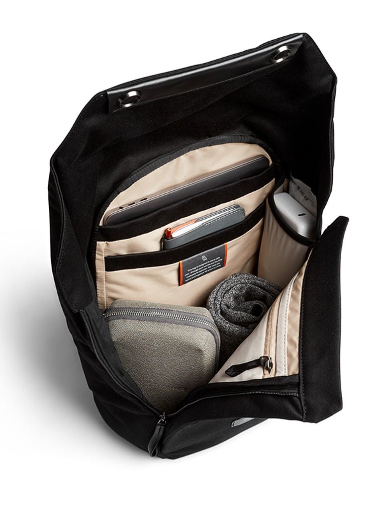 Unzip the Bellroy Melbourne Backpack Compact 13L to reveal its organized beige interior with multiple compartments for a rolled-up towel, zip pouch, power bank, phone, notebook, and other essentials.
