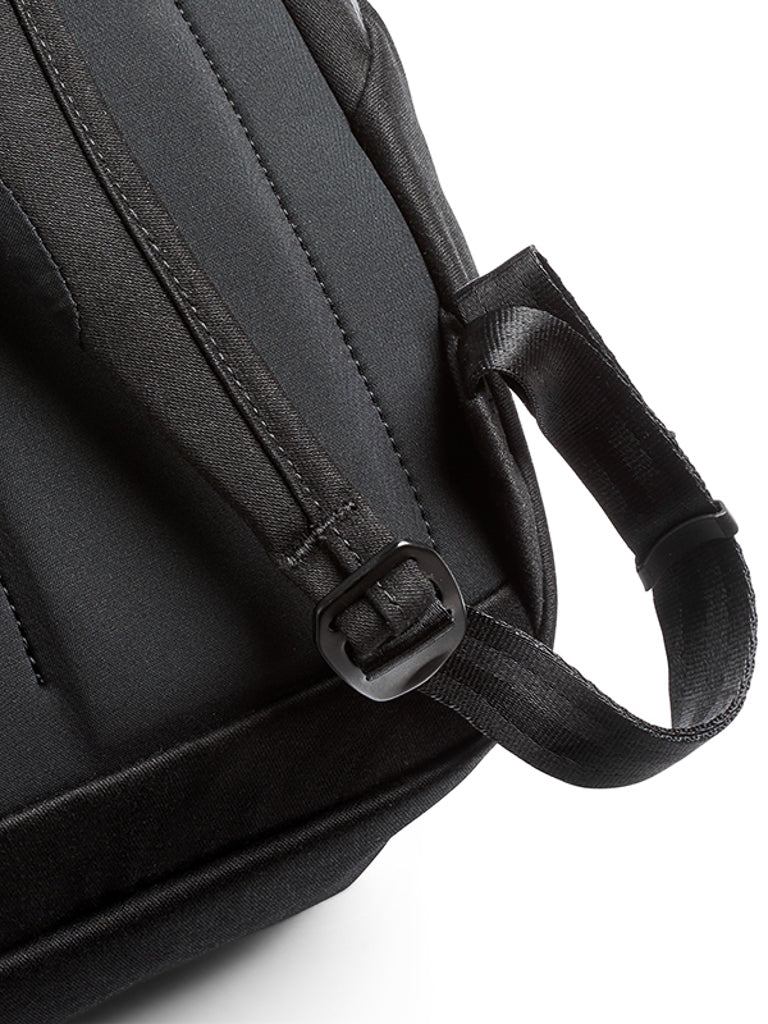 Close-up of the Bellroy Melbourne Backpack Compact 13L in black, featuring a padded shoulder strap and plastic adjustment buckle, shown against a white background.