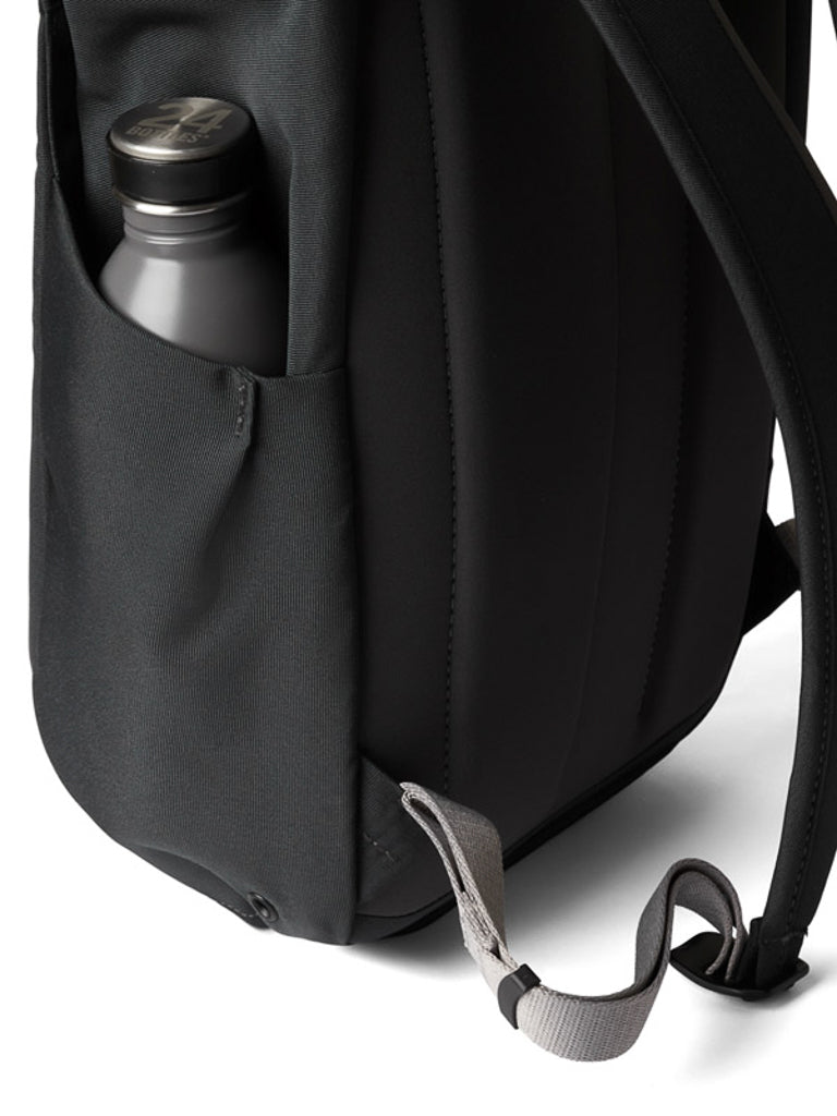 A close-up shows the Bellroy Melbourne Backpack Compact 13L’s side pocket with a stainless steel water bottle, plus a gray strap and part of the padded back panel and shoulder strap.