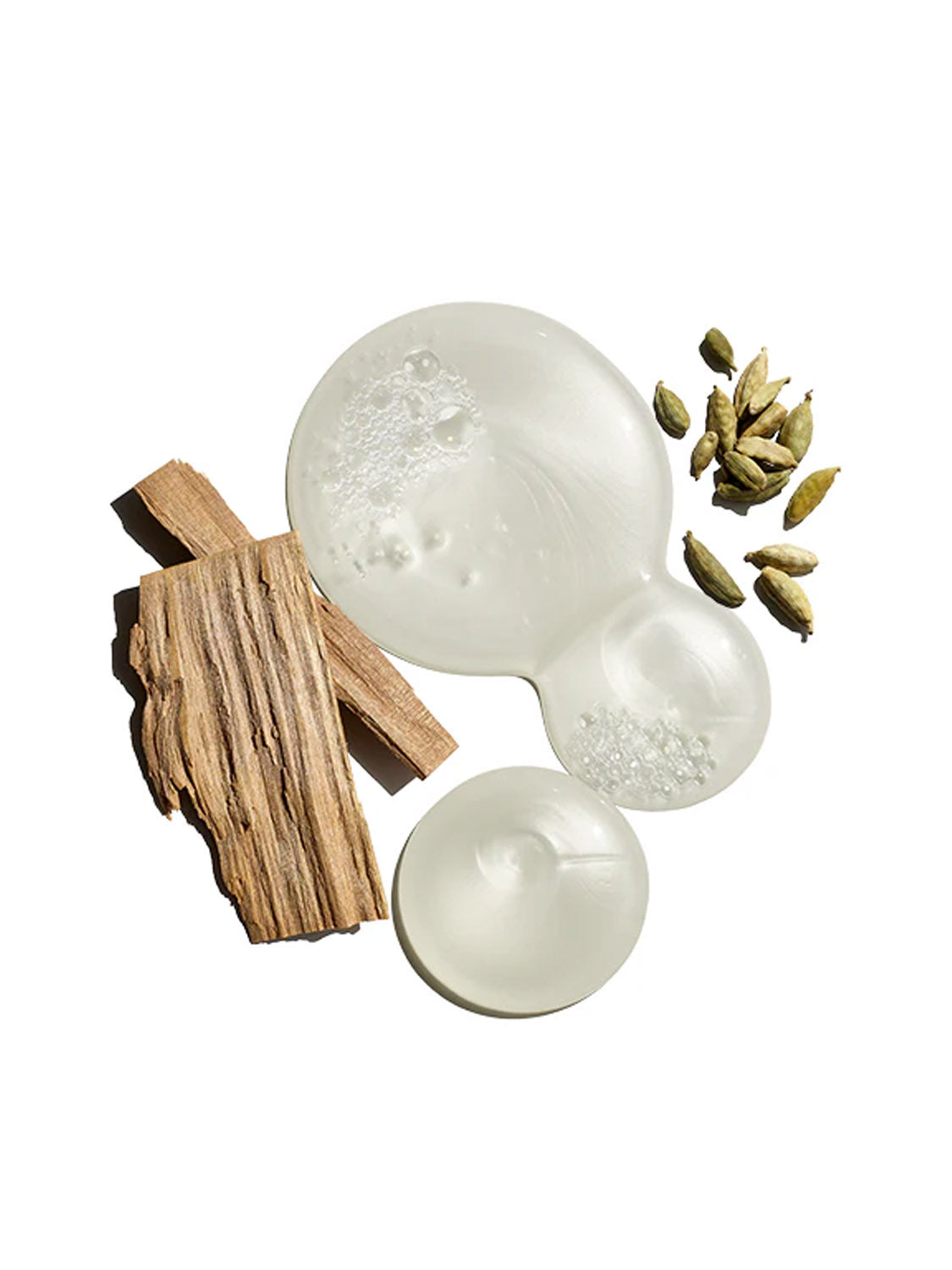 Clear, bubbly liquid pools beside wood pieces and green cardamom pods highlight Jack Black Black Reserve™ Body & Hair Cleanser 10oz, elegantly arranged on a white background.