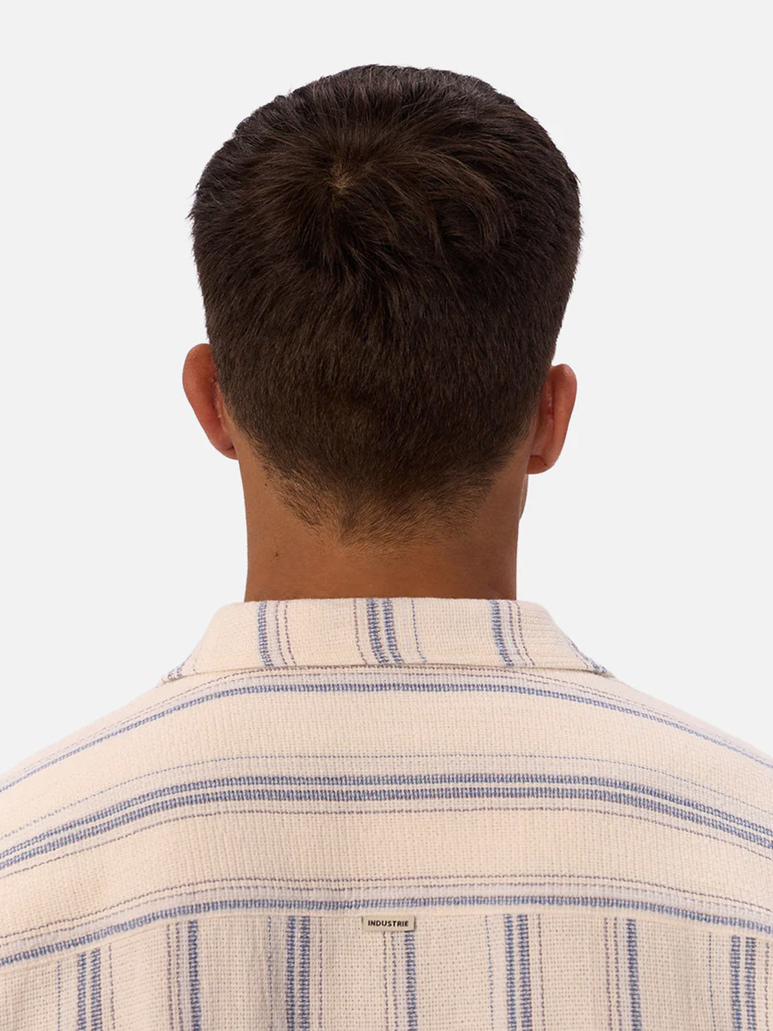 A person with short brown hair is seen from behind wearing the Industrie Bowment Short Sleeve Shirt, crafted in cream-colored breathable cotton with blue stripes, set against a plain white background.