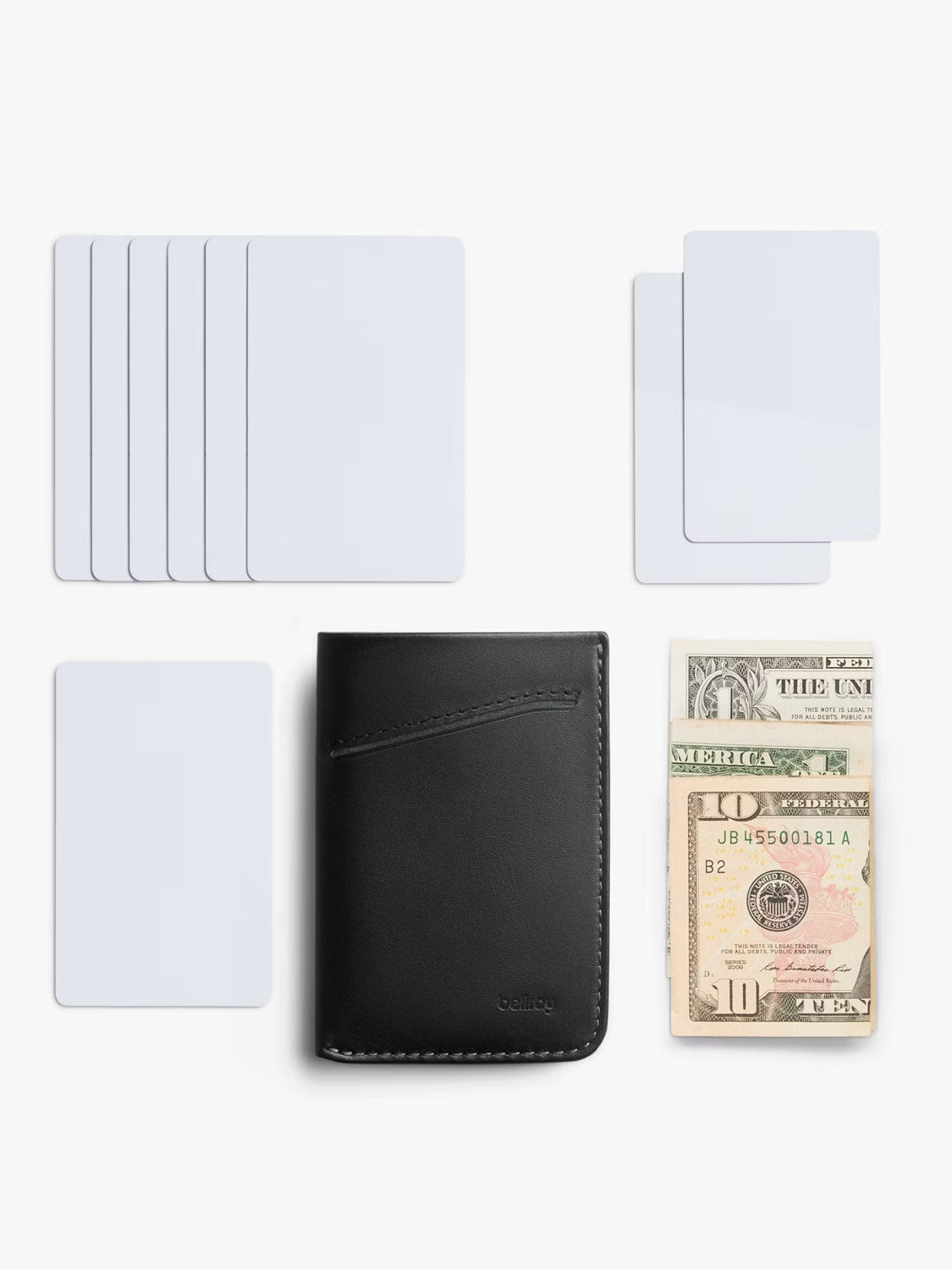A Bellroy Card Sleeve Wallet in black is displayed on a white surface, with blank cards arranged on three sides and various US dollar bills positioned to the right.