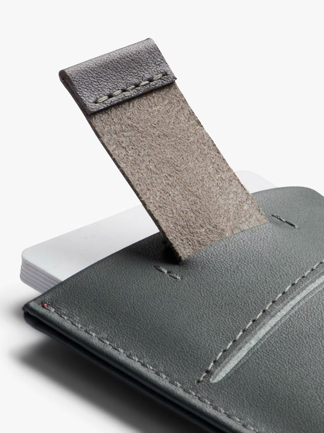 A close-up of the Bellroy Card Sleeve Wallet in gray leather, showing its pull-tab partially lifted to reveal white cards inside—an ideal minimalist accessory combining style and function.