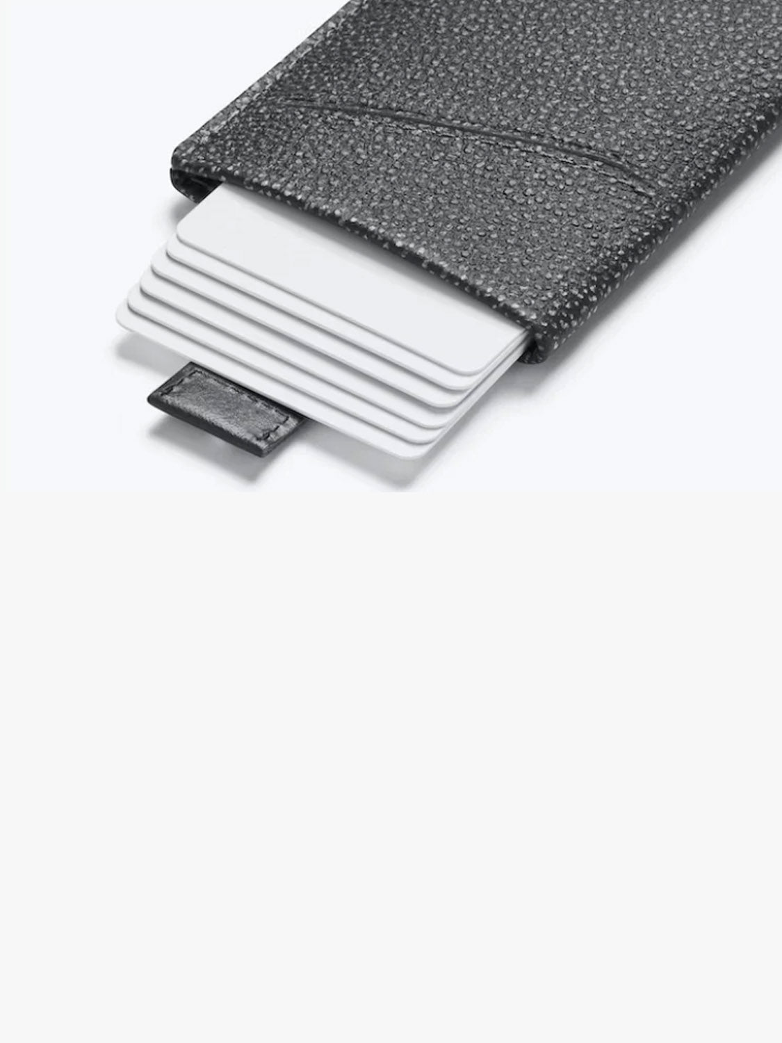 Bellroy’s Card Sleeve Wallet, crafted in black textured leather, displays multiple white cards fanned from its open end against a plain light background.