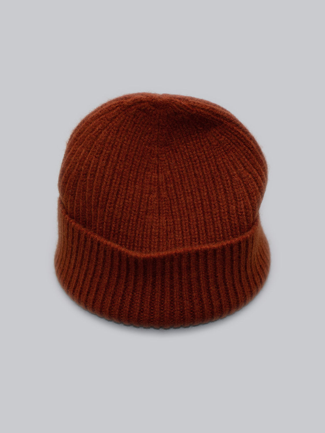 A brown ID Menswear Chamonix Wool Beanie is shown on a plain gray background, made from 100% wool with a ribbed texture, providing natural insulation for a soft and warm feel.