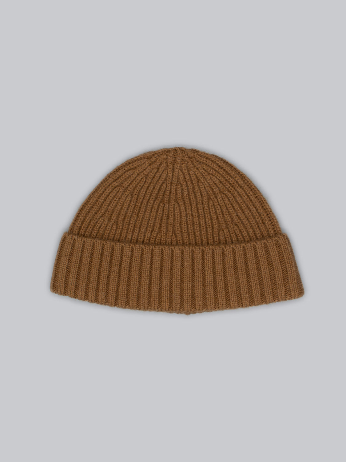 The brown Cho Oyu Merino Wool Fishermans Beanie by ID Menswear, made of cozy merino wool with a ribbed pattern on a light grey background, features a folded brim for a classic touch—an essential for any winter wardrobe.