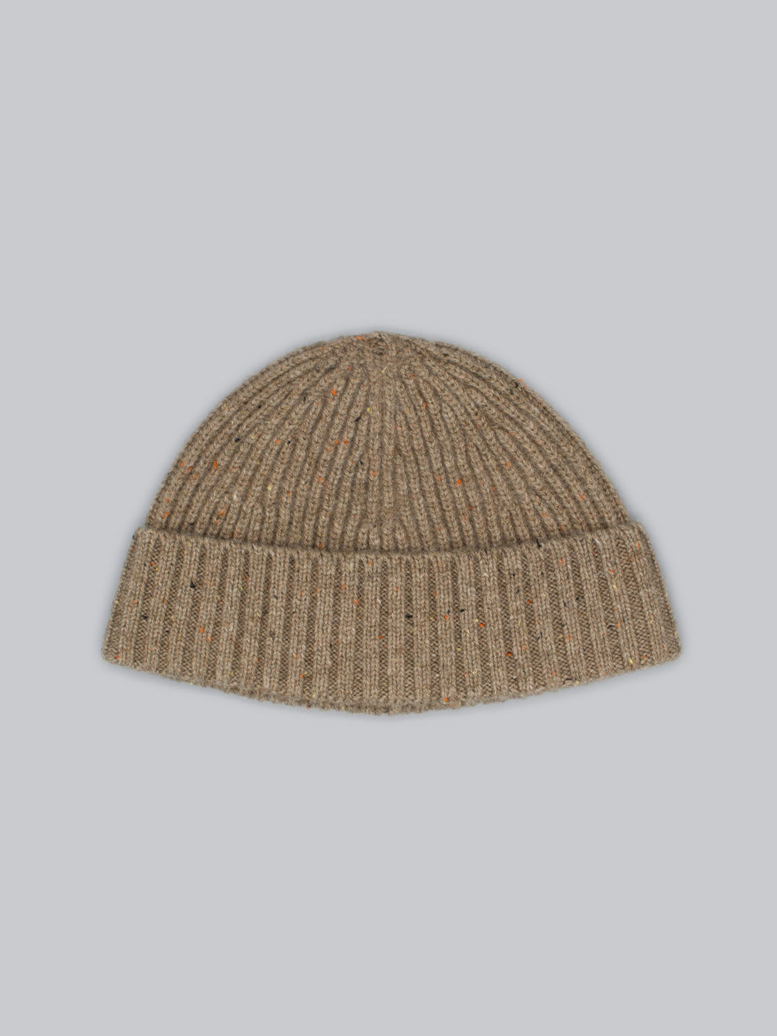 ID Menswears Cho Oyu Merino Wool Fishermans Beanie, in beige with ribbed texture and multicolored specks, is showcased on a light gray background. This stylish winter accessory blends comfort and warmth effortlessly.