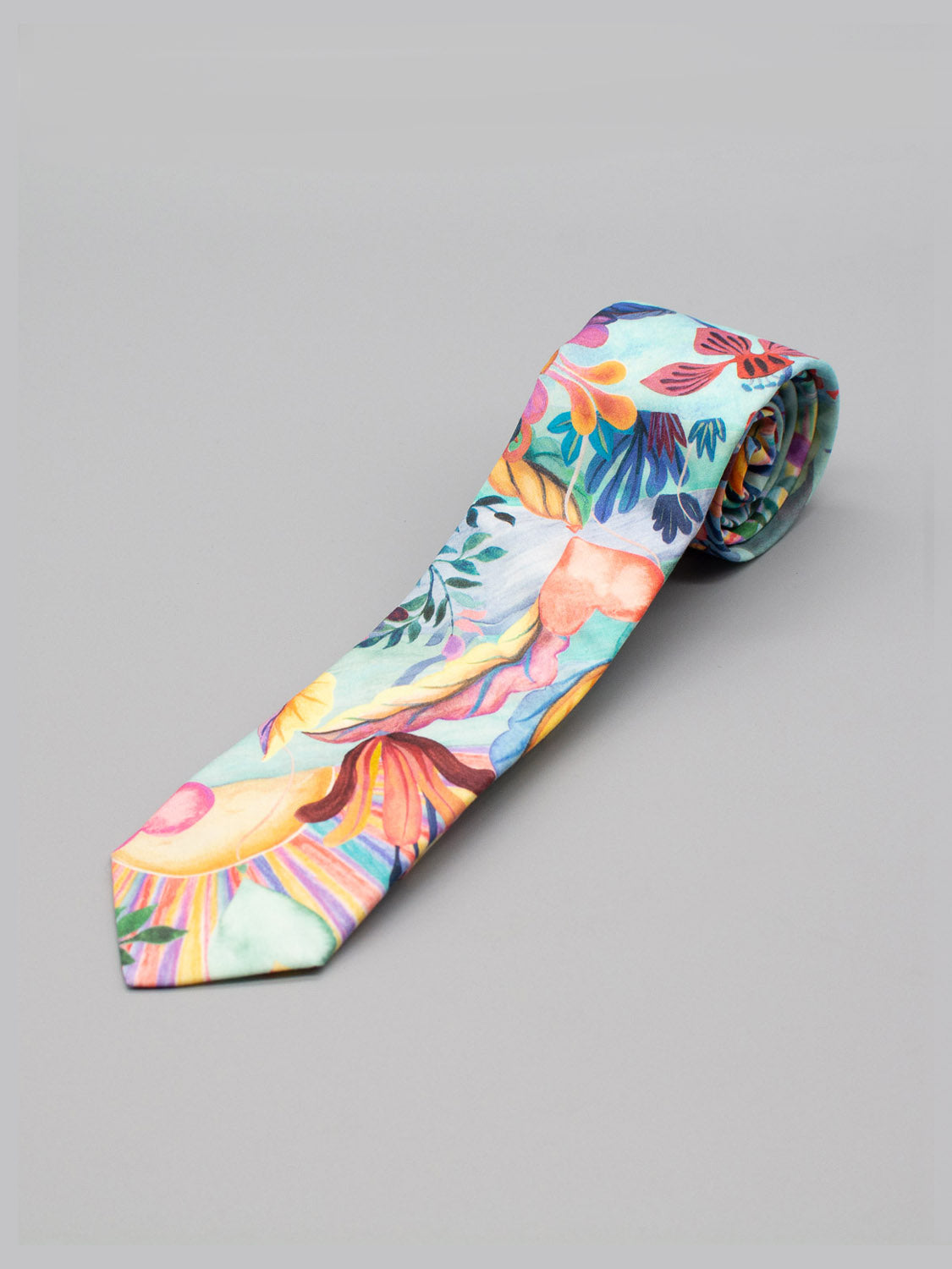 The Liberty of London Tana Lawn™ Una Tie by ID Menswear features a colorful floral and abstract pattern in blue, yellow, red, pink, and green, shown rolled up against a plain gray background.