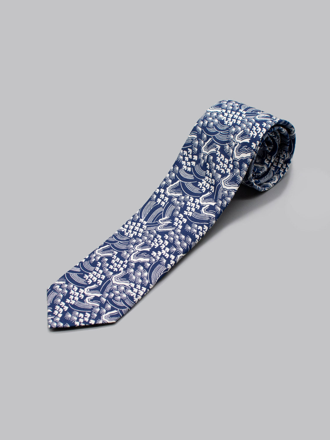 The ID Menswear Liberty of London Tana Lawn™ Hillside tie is handmade from fine cotton, showcasing a navy base with white abstract waves and dot clusters, set against a light gray background.