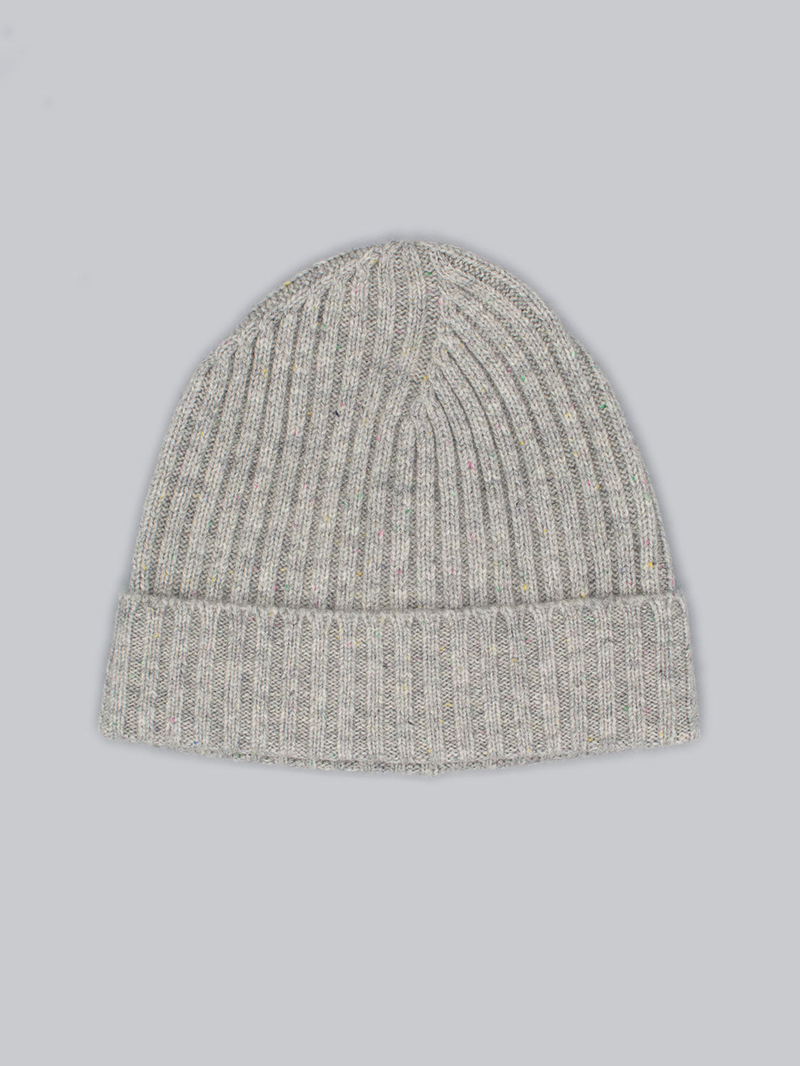 The Kailash Merino Wool Beanie by ID Menswear is a light gray, ribbed knit with a folded brim, made from cozy merino wool for warmth and softness. Displayed on a plain light gray background, its perfect for outdoor adventures.