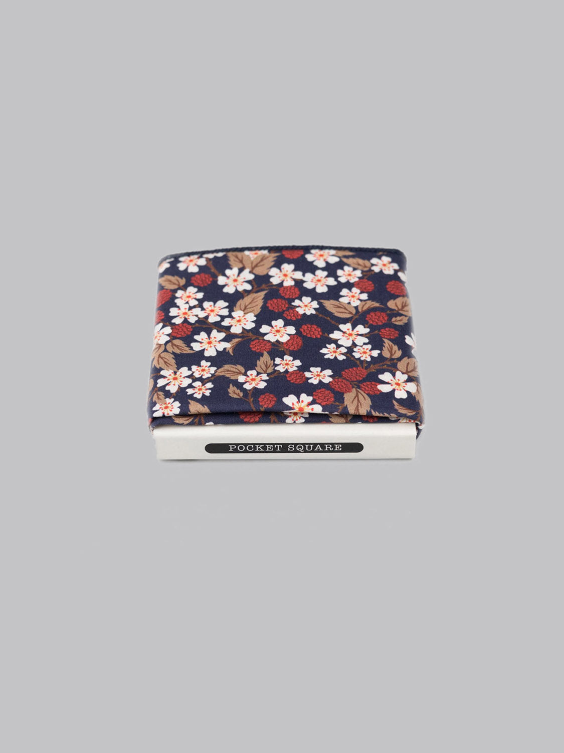 The Liberty™ Karen Pocket Square by ID Menswear, crafted from Tana Lawn cotton with a navy, red, white, and brown floral design, is neatly folded in a white POCKET SQUARE box on a light gray background.