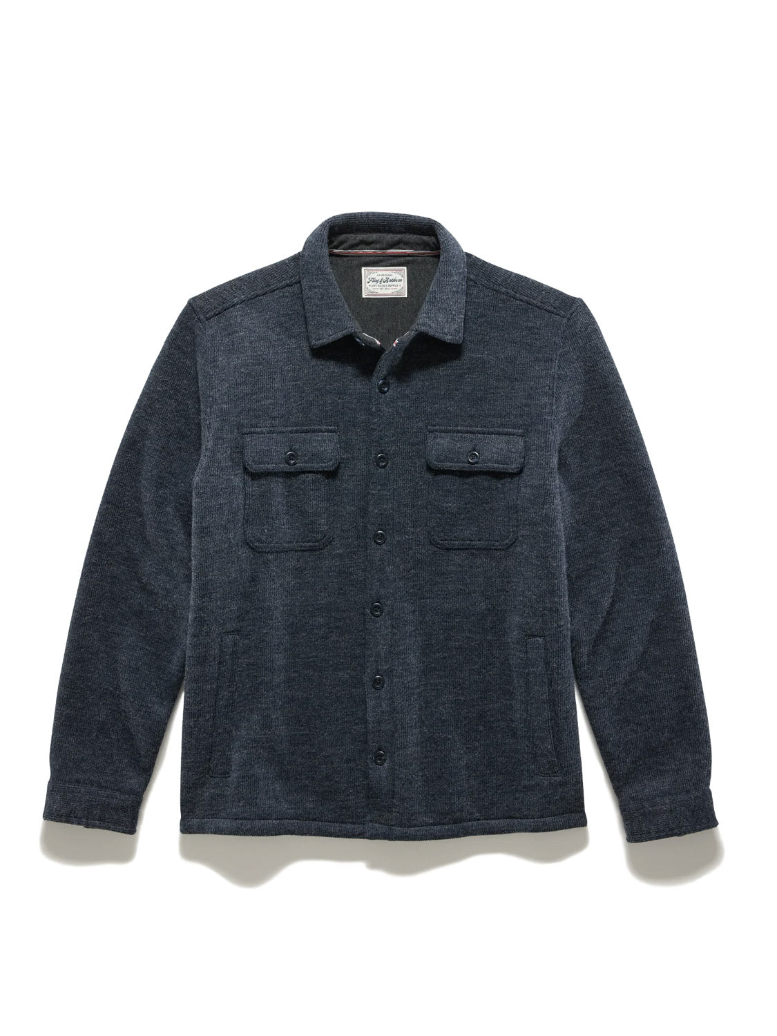 The Flag and Anthem Mason Fleece Lined Shirt Jacket is a dark blue, long-sleeve button-up with two chest pockets, button closures, and a collar. Laid flat on a white background; ideal for men’s outerwear collections.