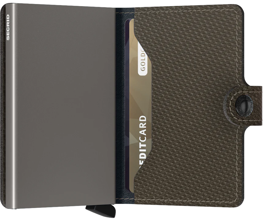 An open Secrid Miniwallet Carbon Weave Pattern Leather displays a credit card partially inserted. This compact wallet features RFID protection, a textured carbon weave exterior, and a snap-button closure on the right side.