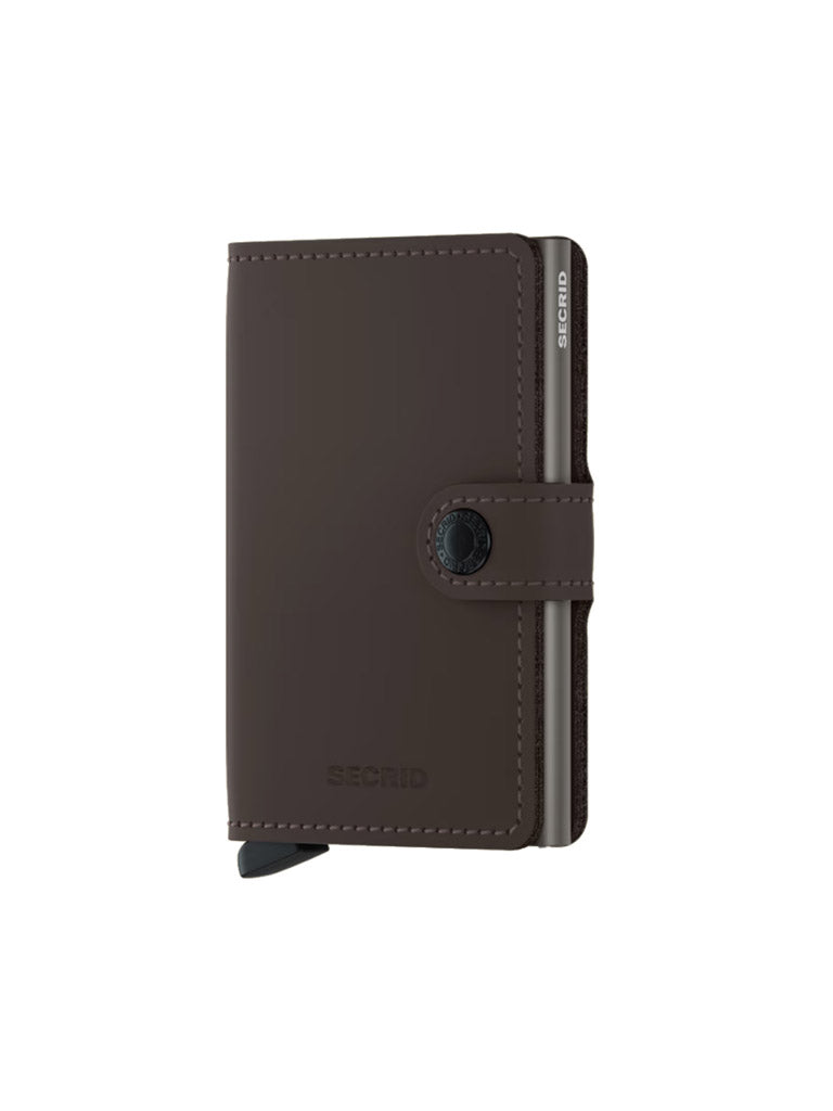 A Secrid Miniwallet Matte Finish Leather, featuring a buttoned strap and metallic edge, stands upright on a white background—a sleek, compact wallet with RFID protection.