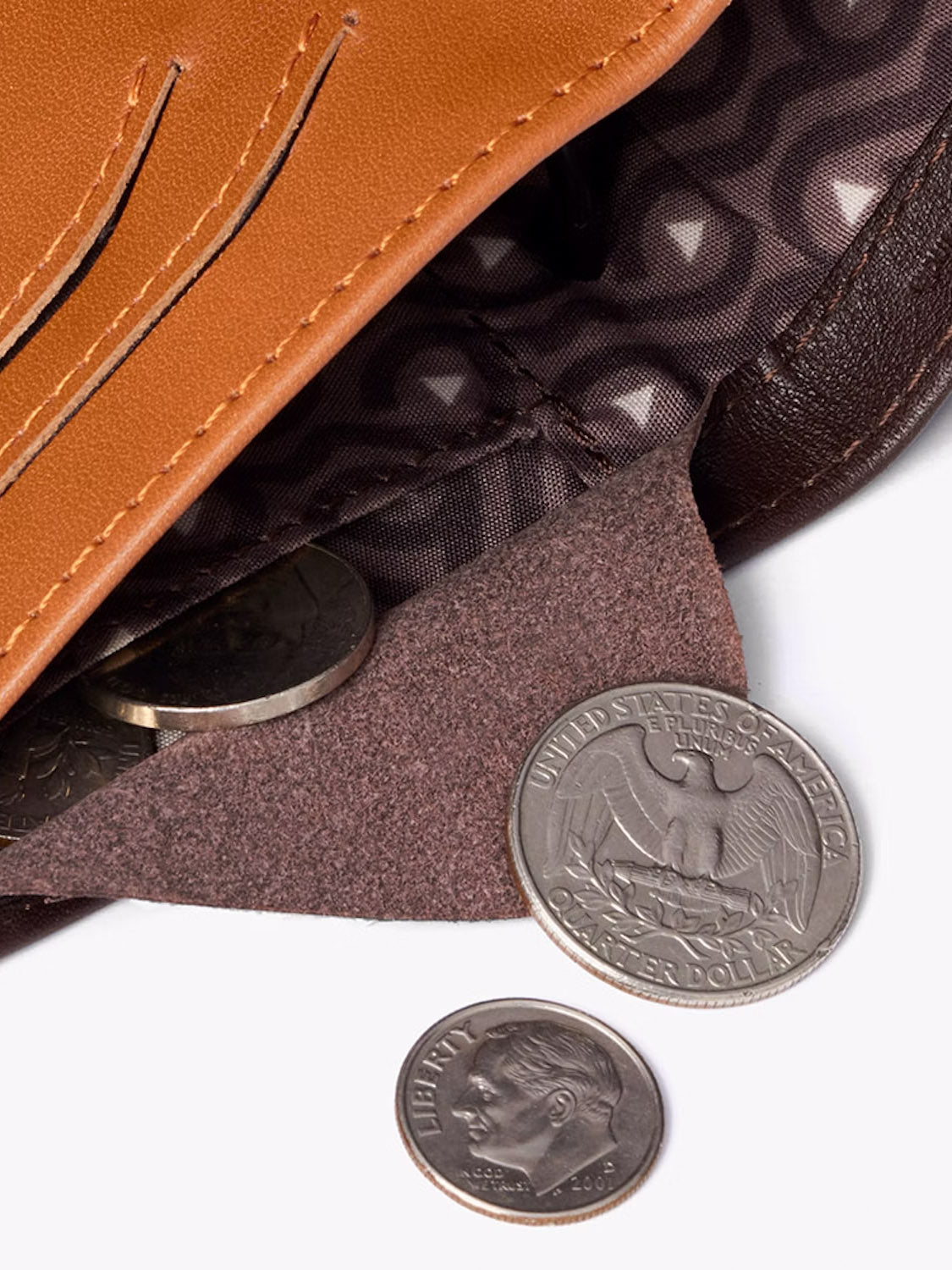 A close-up of the Bellroy Note Sleeve Wallet with coins partially inside and a quarter and dime outside on a white surface. Its patterned lining offers style and RFID protection for added security.