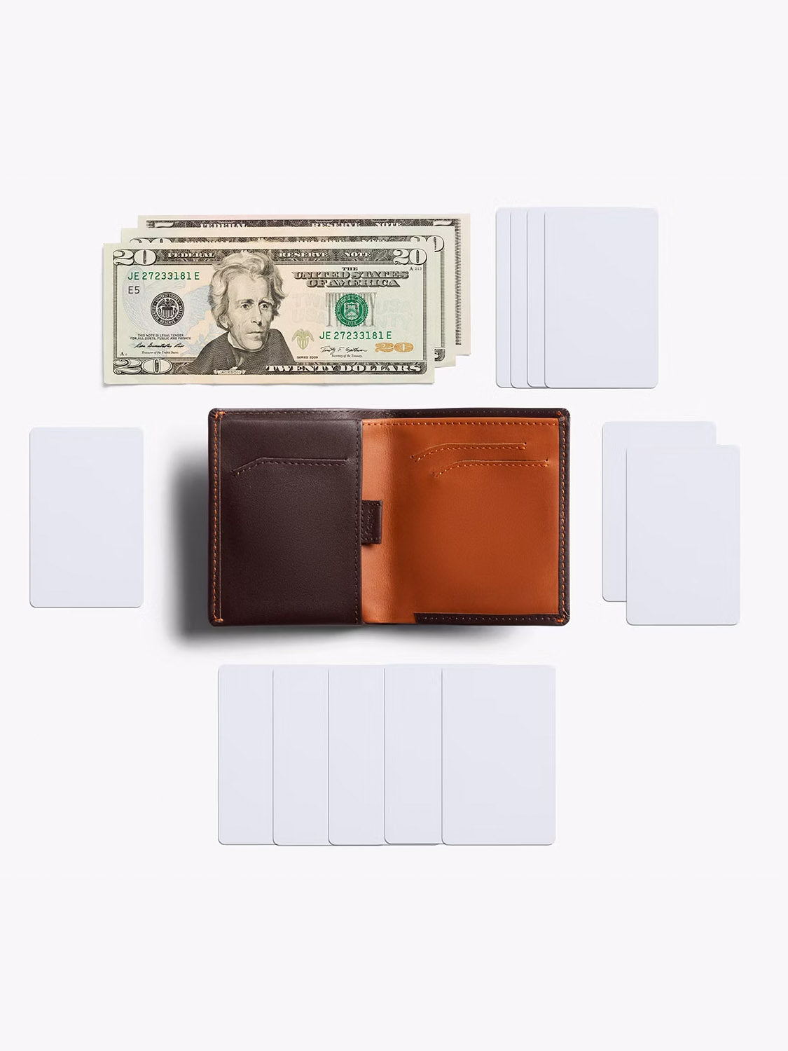 The Bellroy Note Sleeve Wallet in brown leather is open on a white background, surrounded by several blank white cards, with four twenty-dollar bills neatly placed above it.
