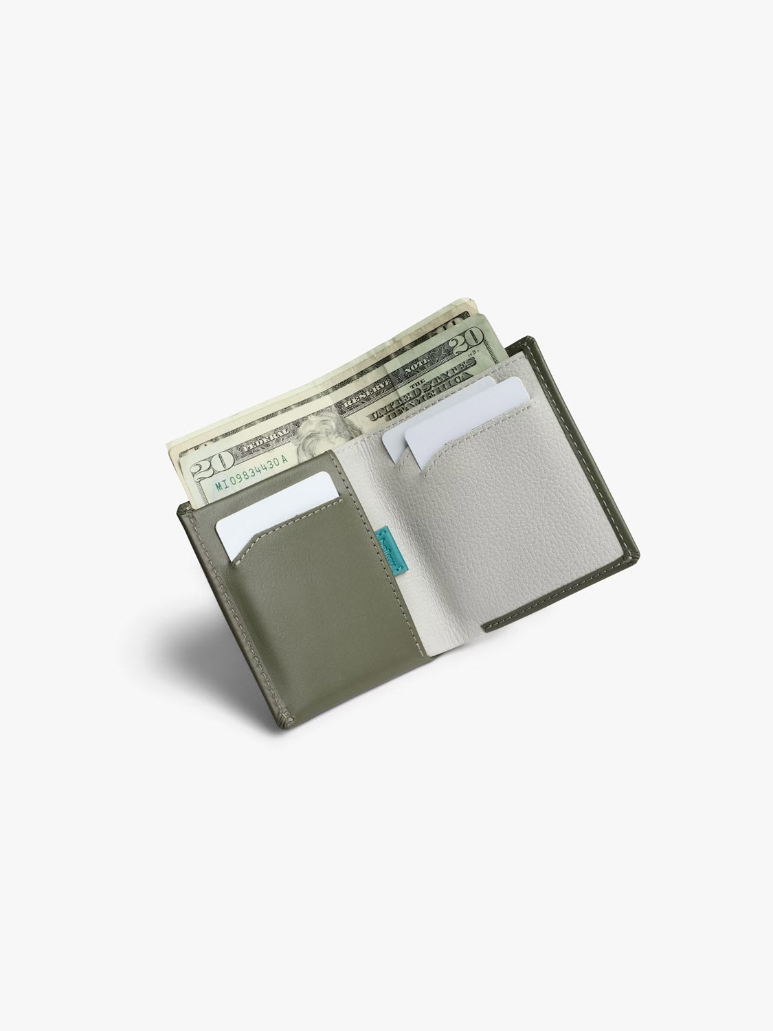 The Bellroy Note Sleeve Wallet, in green and gray, is shown open on a white background with cash, a card, and papers in its compartments.