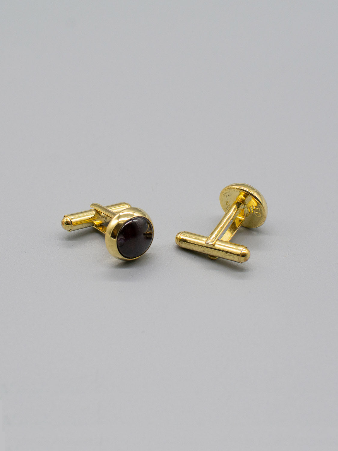 ID Menswears Gold Plated Silver Gemstone Cufflinks are stylishly displayed on a gray surface. One stands upright, highlighting its face, while the other rests flat, showing the T-bar and bullet back mechanism.