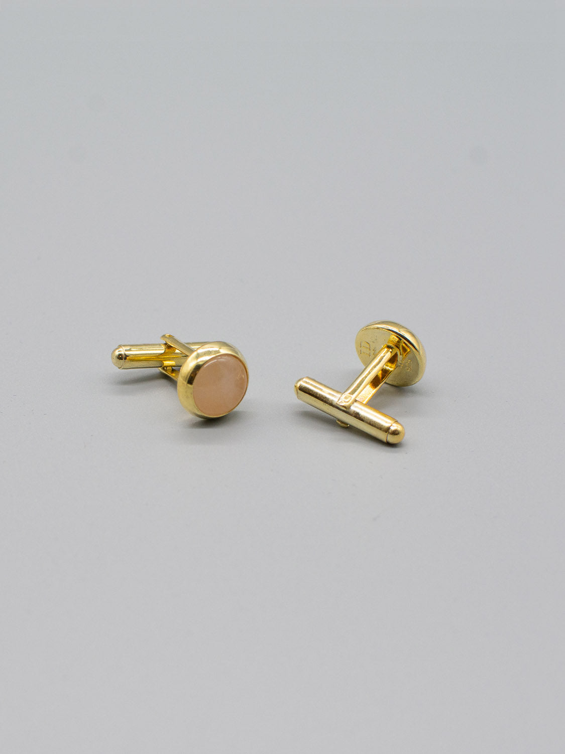 Two ID Menswear Gold Plated Silver Gemstone Cufflinks with oval tops sit on a flat gray surface. The polished, shiny finish subtly reflects light. Featuring a bullet back mechanism, they offer a simple and elegant design, perfect for formal wear.