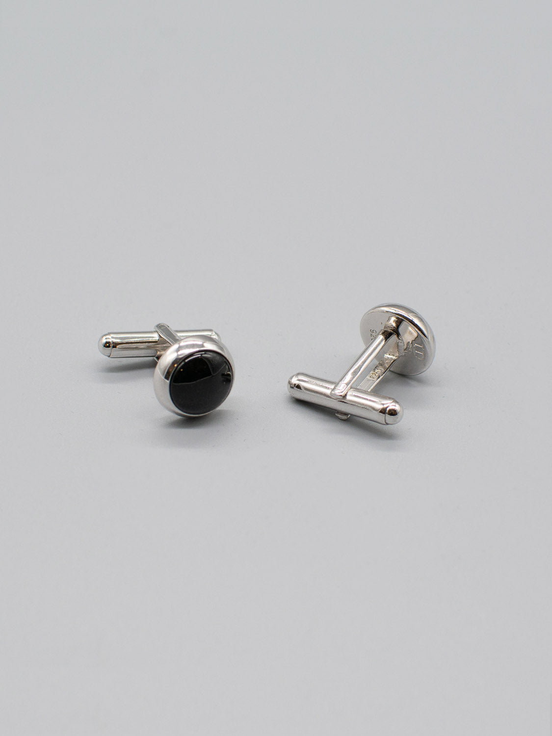 ID Menswears Silver Gemstone Cufflink, featuring sterling silver with rhodium plating and round black centers, is elegantly displayed on a plain gray background.