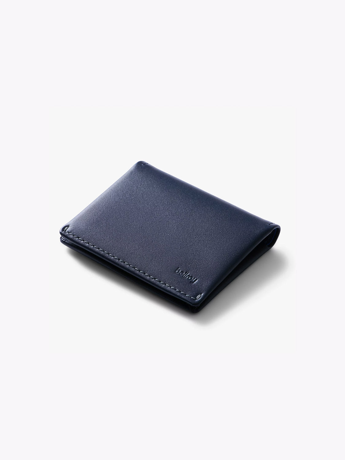 A closed Bellroy Slim Sleeve Wallet in dark blue, featuring subtle stitching and a small embossed logo in the lower right corner, set against a plain white background.