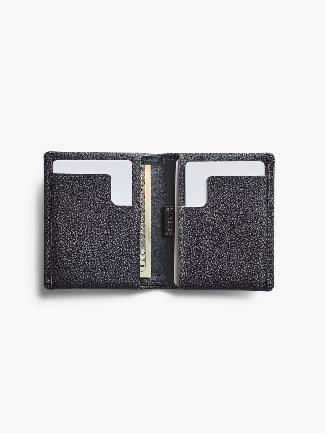 The Bellroy Slim Sleeve Wallet in black textured leather features two card slots, each holding a white card, and a center bill compartment. This sleek wallet is shown open on a plain white background.