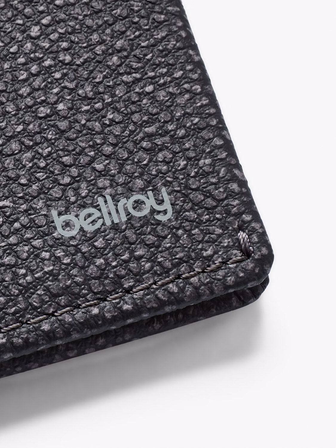 Close-up of a textured black Slim Sleeve Wallet by Bellroy, featuring light gray branding and visible corner stitching that highlights its slim, pocket-friendly design.