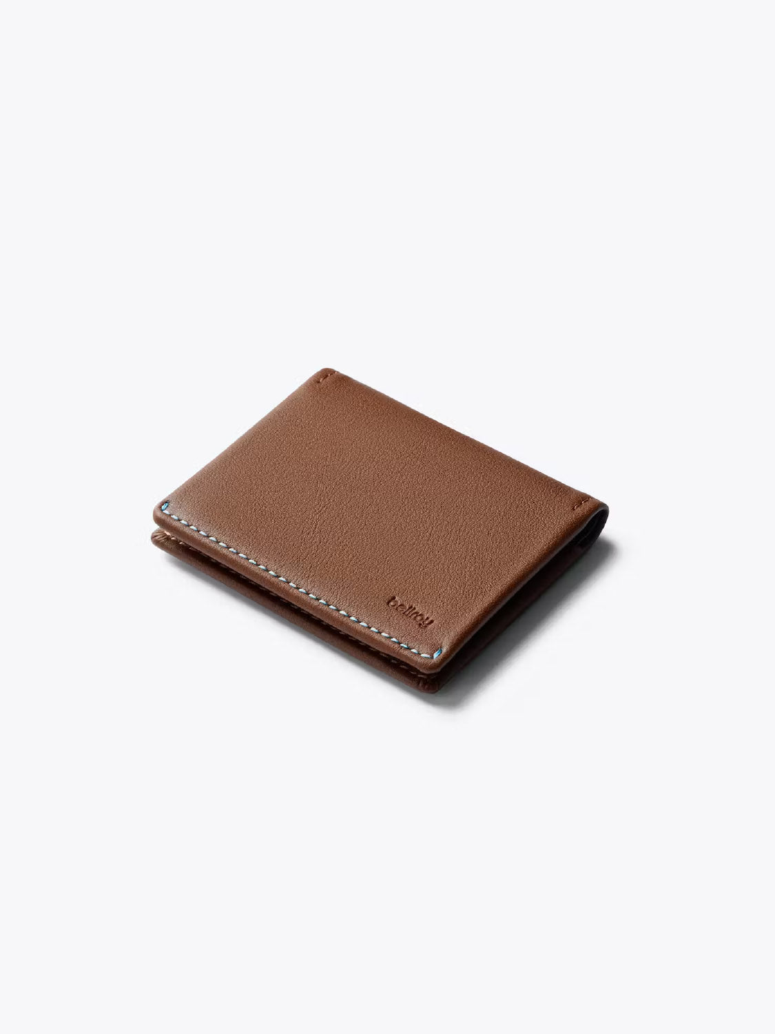 The Bellroy Slim Sleeve Wallet, crafted from brown leather with visible edge stitching, is shown closed on a light gray background.