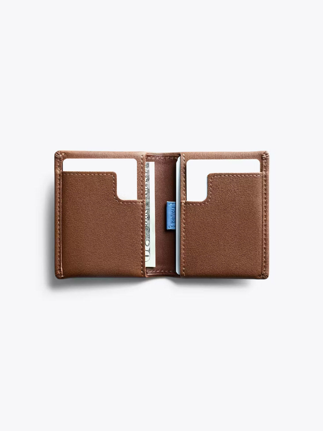 The Bellroy Slim Sleeve Wallet in brown features an open design with two card slots holding white cards and a partially visible banknote in the center pocket, displayed on a light gray background.